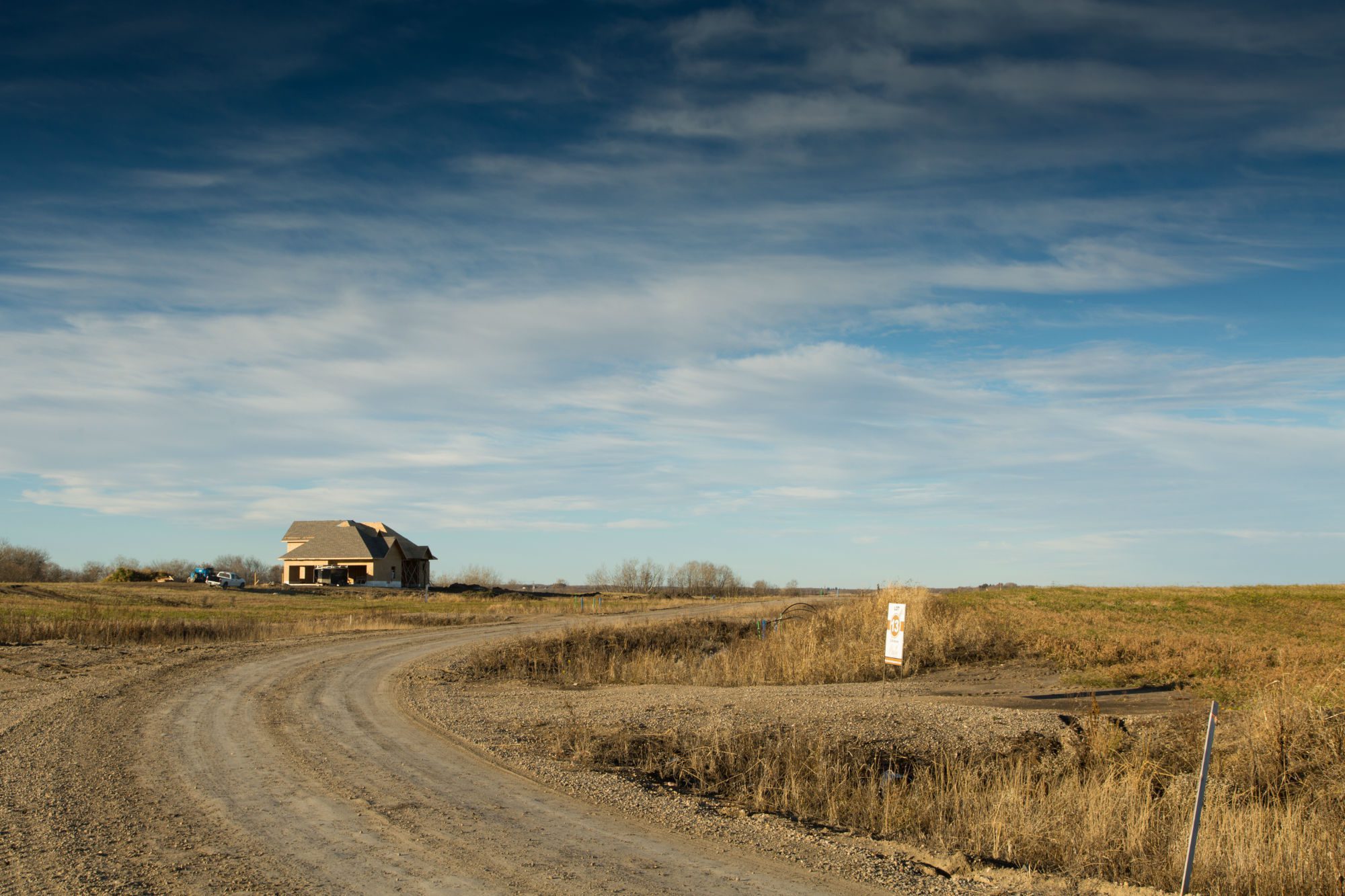 Gravel road through Brylee Estates with a home on the horizon