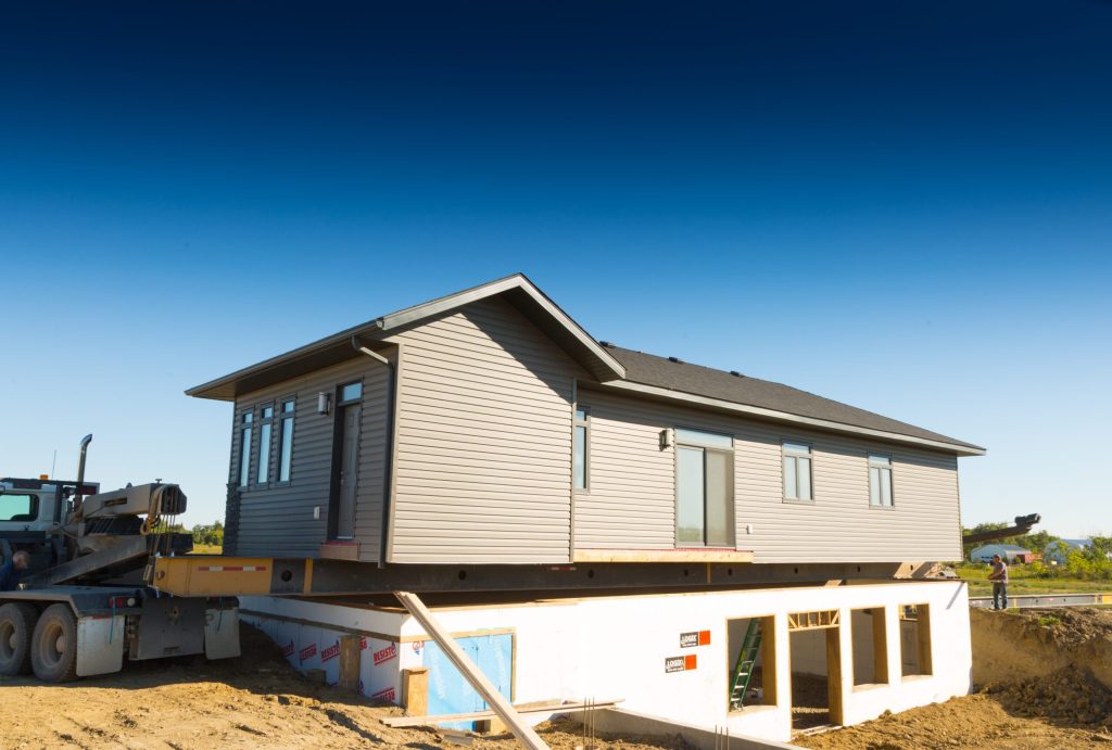Ready-to-move home on a trailer being set on its foundation at Brylee Estates